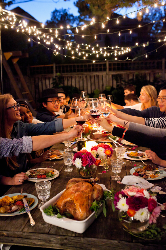 Friends enjoying dinner outside, raising their glass for a toast.