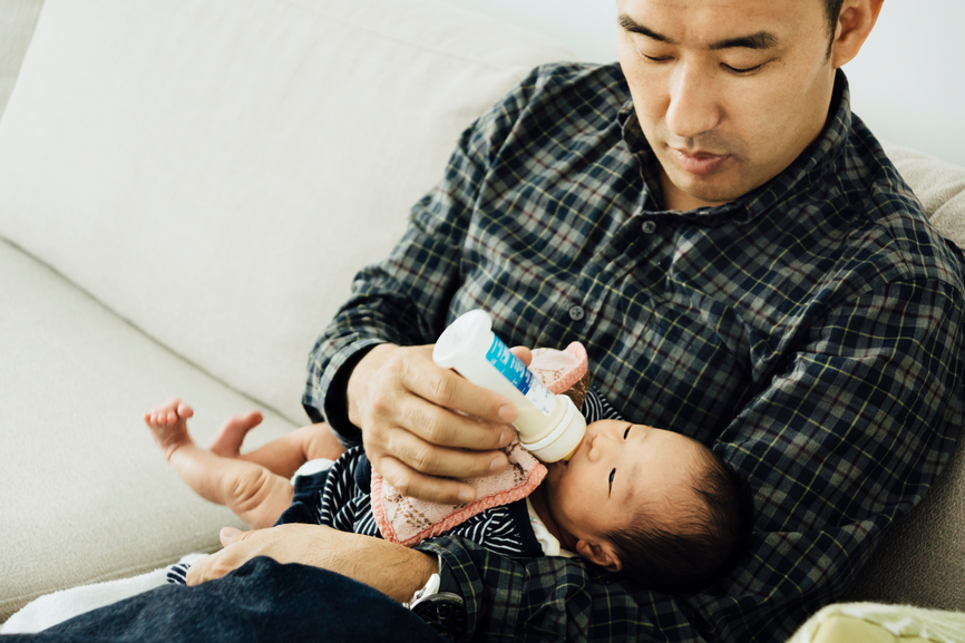 Asian father, feeding milk to a 10-day-old newborn baby girl